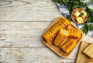 Delicious grilled corn cobs on white wooden table, flat lay. Space for text