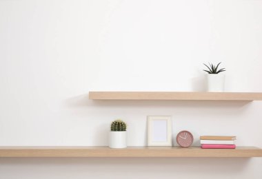 Wooden shelves with books and decorative elements on light wall