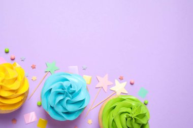 Colorful birthday cupcakes on lilac background, flat lay. Space 
