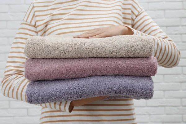 Mulher segurando toalhas frescas contra parede de tijolo branco, close-up — Fotografia de Stock