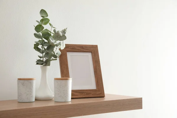 Wooden shelf with photo frame and decorative elements on light w — Stock Photo, Image