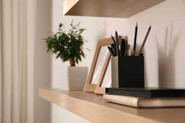 Wooden shelves with books and decorative elements on light wall — 스톡 사진