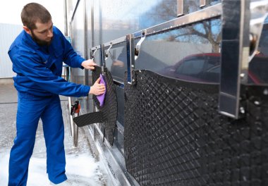 Araba yıkamada araba paspası silen işçiler