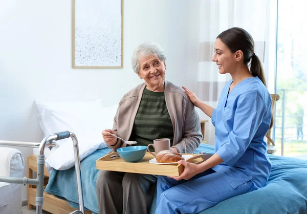 Cuidador sirviendo cena para anciana en geriatría hospic — Foto de Stock