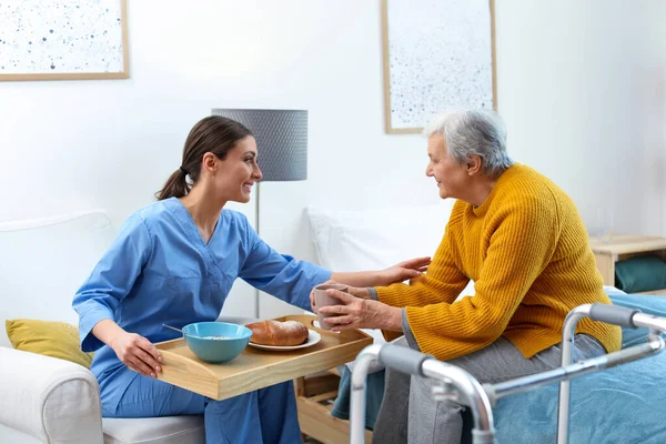 Travailleur soignant servant le dîner pour une femme âgée en hospice gériatrique — Photo