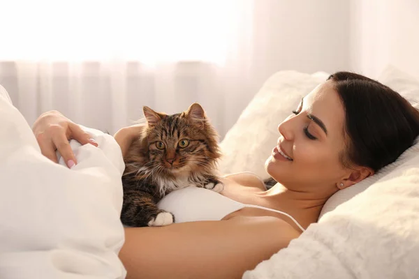 Mooie jonge vrouw met haar schattige kat op bed. pluizig huisdier — Stockfoto