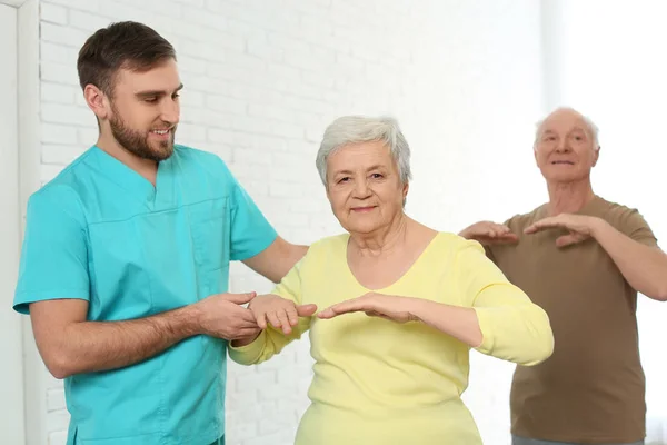 Cuidador ajudando a mulher idosa a fazer exercício esportivo em hospi — Fotografia de Stock