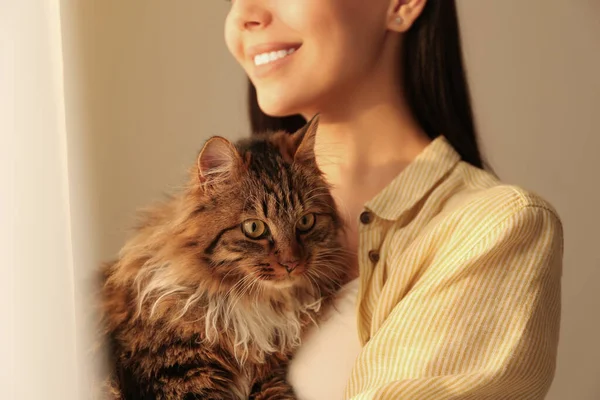 Mooie vrouw met haar schattig kat op beige achtergrond, close-up. — Stockfoto