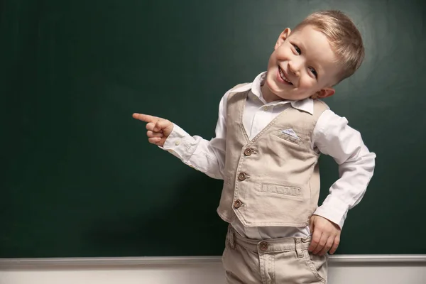 Pequeño niño divertido cerca de pizarra, espacio para el texto. Primera vez a —  Fotos de Stock