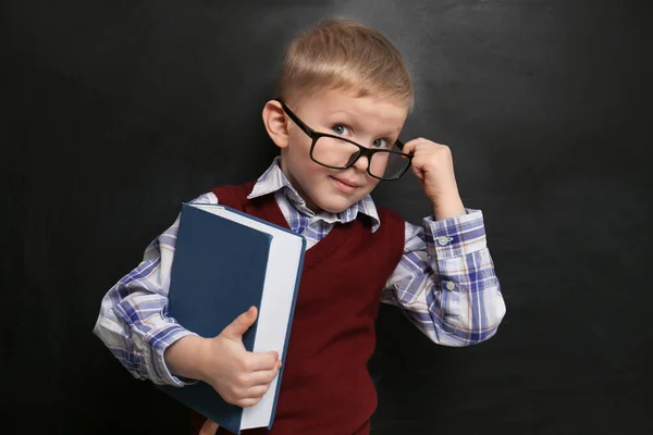 Lindo niño pequeño con gafas cerca de pizarra. Primera vez en —  Fotos de Stock