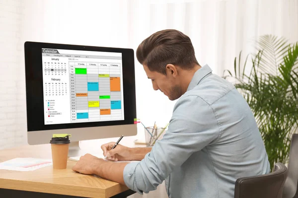 Hombre guapo planeando su horario con la aplicación de calendario en el ordenador —  Fotos de Stock