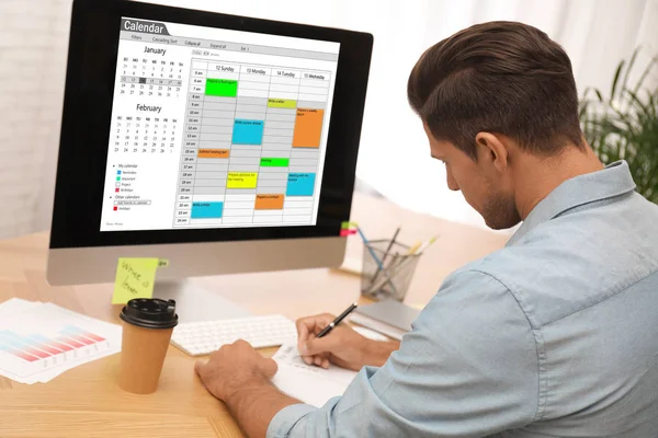 Hombre planeando su horario con la aplicación de calendario en el ordenador en offic —  Fotos de Stock