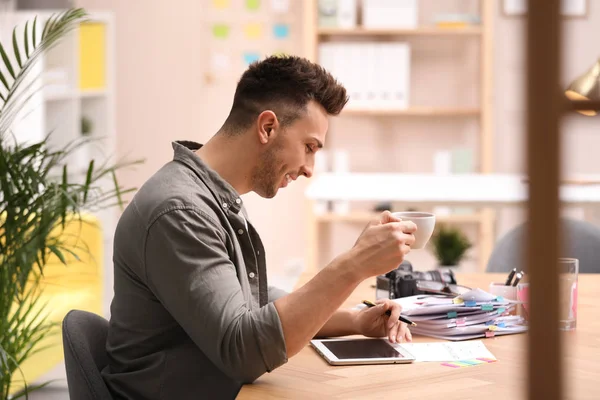 Journalist with tablet and coffee at workplace in office