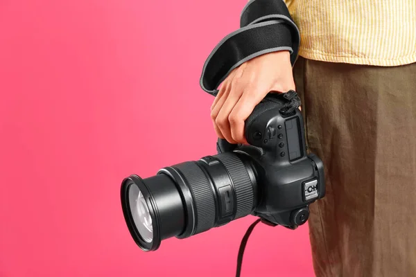 Professional photographer with modern camera on pink background