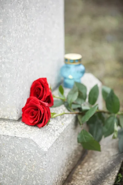 Röda rosor på gammal grå gravsten utomhus. Begravning — Stockfoto