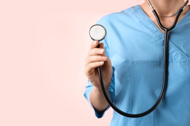 Pembe arka planda steteskobu olan doktor, yakın plan. Tıbbi hizmet