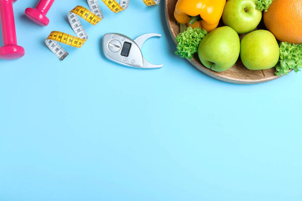 Fruits, dumbbells, measuring tape and digital caliper on light blue background, flat lay with space for text. Visiting nutritionist