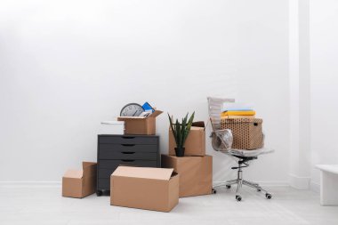 Karton kutular ve beyaz duvarın yanındaki eşyalar. Taşınma günü