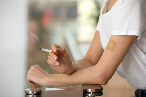 Giovane donna con cerotto alla nicotina e sigaretta al chiuso, primo piano — Foto Stock