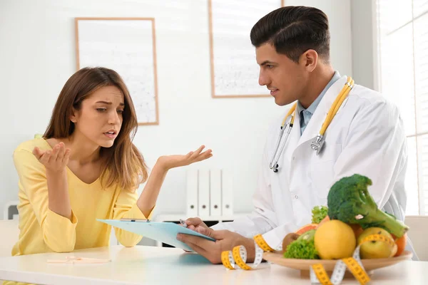 Nutricionista consulta paciente à mesa na clínica — Fotografia de Stock