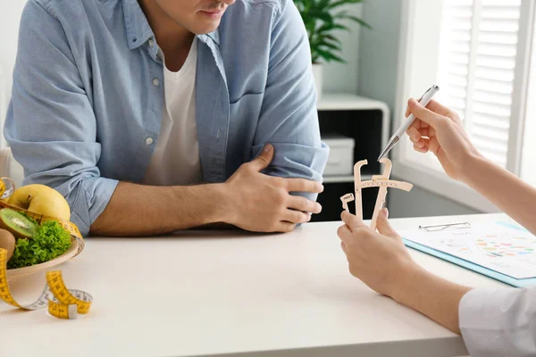 Young nutritionist consulting patient at table in clinic, closeu — Stock Photo, Image