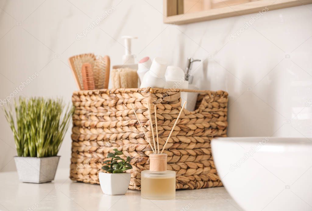 Different toiletries and green plants on countertop in bathroom
