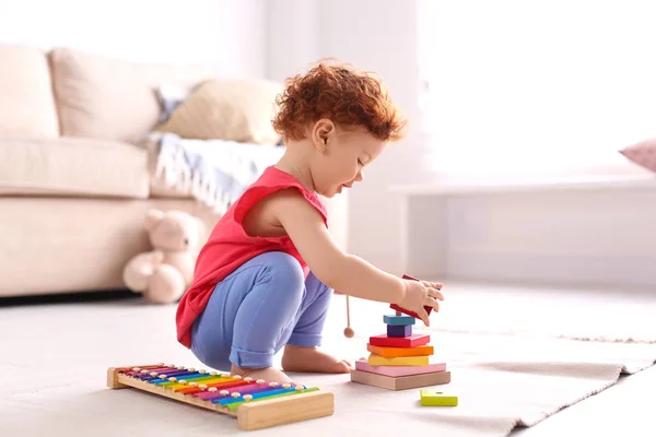 Lindo niño pequeño jugando con juguetes en el suelo en casa — Foto de Stock