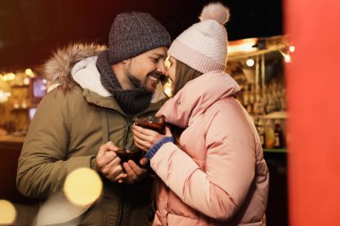 Happy couple with mulled wine at winter fair