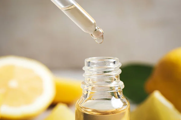 Citrus essential oil dripping from pipette into bottle, closeup