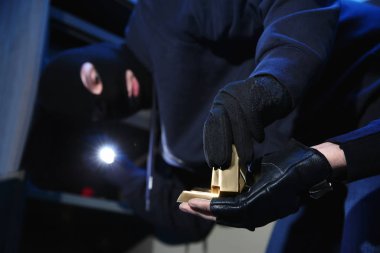 Hırsızlar gece vakti çelik kasadan altın çubuklarını çıkarıyorlar.