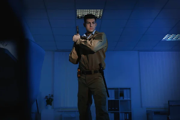 Profesjonalny ochroniarz z pistoletem w ciemnym biurze — Zdjęcie stockowe
