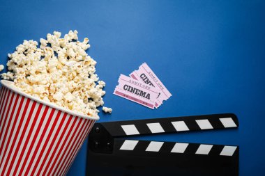 Mavi arka planda lezzetli patlamış mısır ve sinema malzemeleriyle düz kompozisyon.