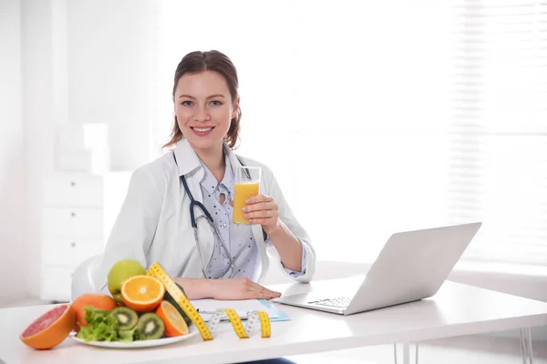Διατροφολόγος με ποτήρι χυμό και laptop στο γραφείο — Φωτογραφία Αρχείου