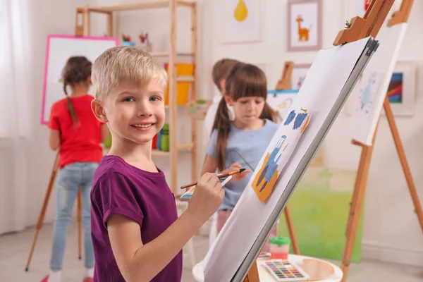 Cute little child painting during lesson in room