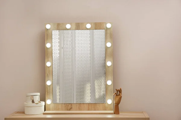 Стильное зеркало с лампочками возле бежевой стены — стоковое фото