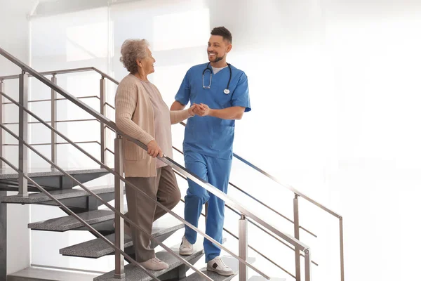 Médico ayudando a paciente mayor en hospital moderno —  Fotos de Stock