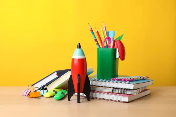 Foguete de brinquedo brilhante e material escolar na mesa de madeira — Fotografia de Stock