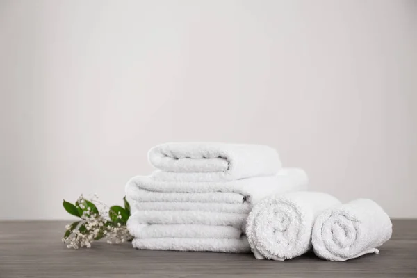 Fresh white towels and green plant on grey wooden table — Stock Photo, Image