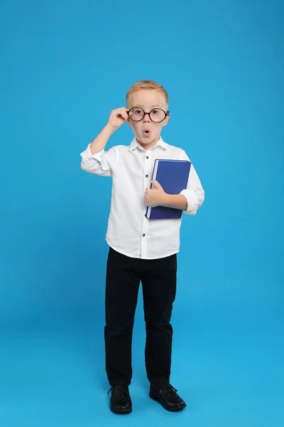 Full längd porträtt av söt liten pojke med bok om ljusblå — Stockfoto