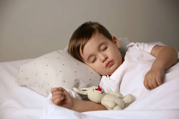 Мила маленька дитина спить з іграшкою вдома. Ліжко — стокове фото