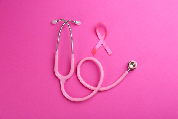 Pink ribbon as breast cancer awareness symbol and stethoscope on color background, flat lay