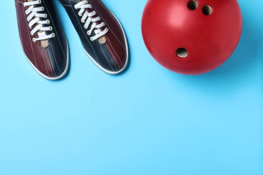 Bowling topu ve açık mavi arka planda ayakkabılar, düz yatış. Boşluk