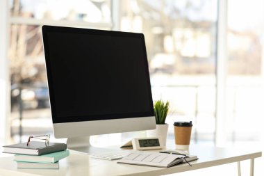 Bilgisayar, defterler ve kahve ofisteki masada.