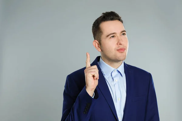 Portrait of emotional young businessman on grey background — Stock Photo, Image