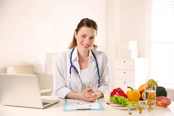 Nutricionista com área de transferência e laptop na mesa no escritório — Fotografia de Stock