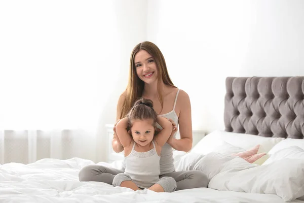 Madre feliz con hija pequeña en el dormitorio — Foto de Stock