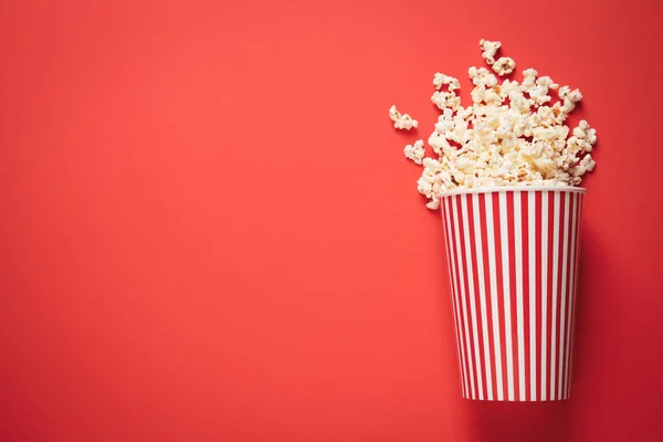 Taza Papel Volcada Con Deliciosas Palomitas Maíz Sobre Fondo Rojo — Foto de Stock