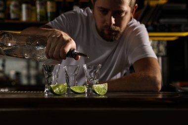 Barmen bardaki shot bardağına Meksika tekilasını dolduruyor, yakın plan.