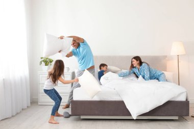 Mutlu aile yatak odasında yastık savaşı yapıyor.