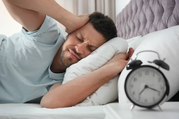 Sleepy man closing ears at home in morning — Stock Photo, Image